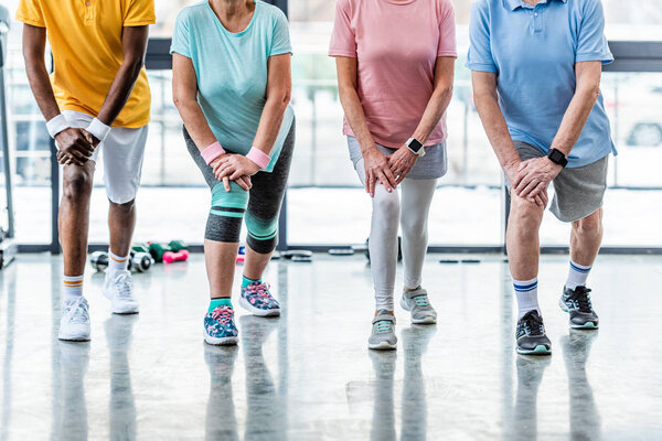 cropped shot of senior sportspeople synchronous stretching at gym