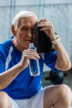 şişe su tutarak ve spor salonunda dinleniyorum havlu tarafından kafa silerek yorgun üst düzey sporcu