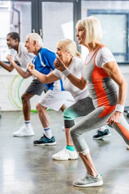 yan görünümü çok ırklı üst düzey sporcu zaman uyumlu spor salonunda egzersiz