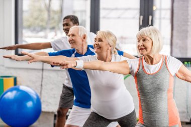 üst düzey çok ırklı sporcu zaman uyumlu spor salonunda egzersiz yan görünüm