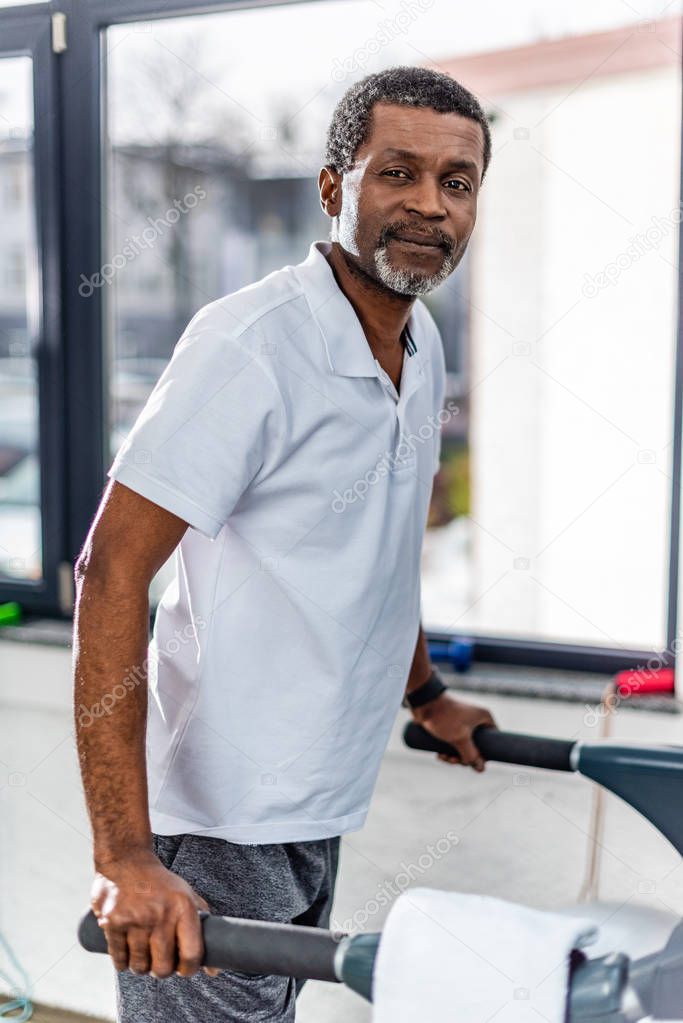 selective focus of middle aged african american man on treadmill at gym