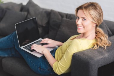 dizüstü bilgisayar ile boş ekran kullanarak ve kameraya gülümseyen güzel mutlu kadın