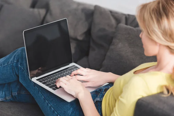 裁剪拍摄的妇女使用笔记本电脑与空白屏幕沙发上 — 图库照片
