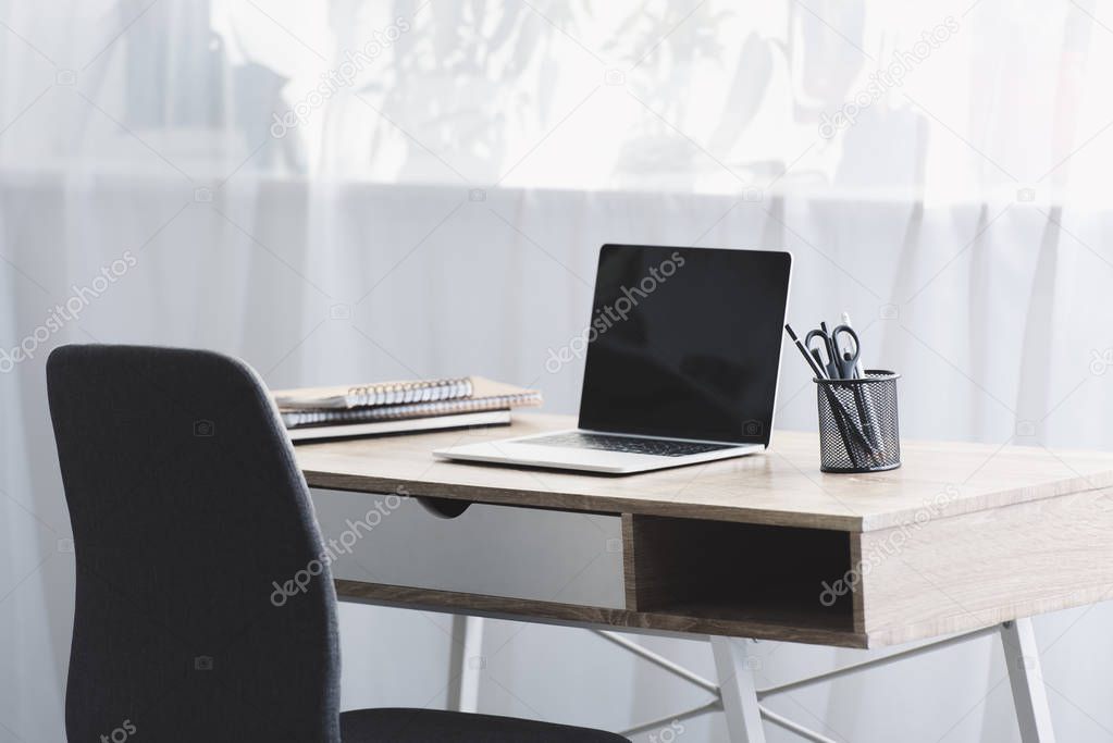 laptop with black screen on wooden table at workplace