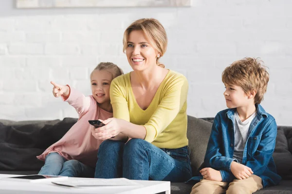 リモート コント ローラーを使用して 一緒にテレビを見て子供たちが笑顔で幸せな母 — ストック写真