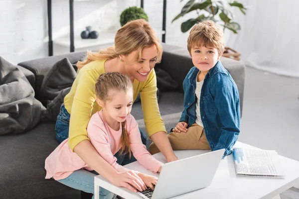 Счастливая Мать Восхитительно Улыбающимися Детьми Использующими Ноутбук Вместе Дома — стоковое фото