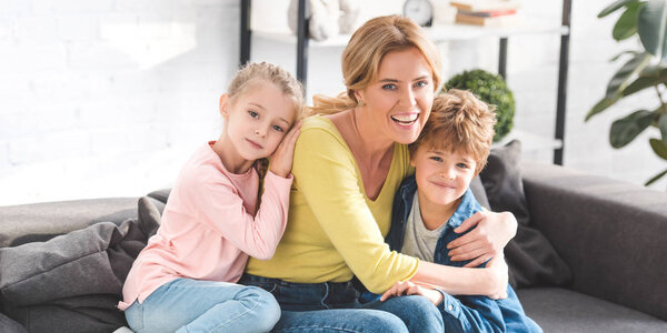 happy mother with adorable children hugging and smiling at camera