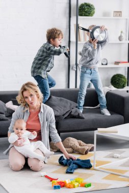 Bebek Çocuk tutarak ve kamera ise yaramaz çocuklar evde oynarken bakarak yorgun anne
