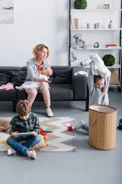 Upset Mother Holding Infant Kid Looking Naughty Siblings Playing Home — Stock Photo, Image