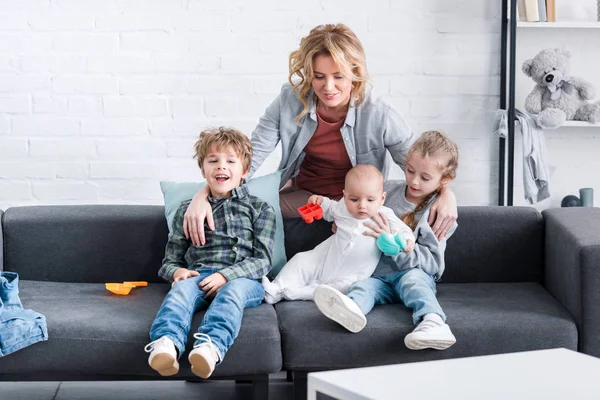 Mère Heureuse Regardant Trois Adorables Enfants Assis Sur Canapé — Photo