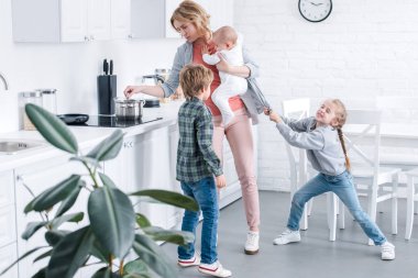 yorgun anne bebek çocuk tutan ve yaramaz çocuk mutfakta oyun süre pişirme 