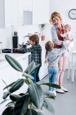 Bebek Çocuk tutarak ve mutfak çocuklarda bakarak yorgun anne