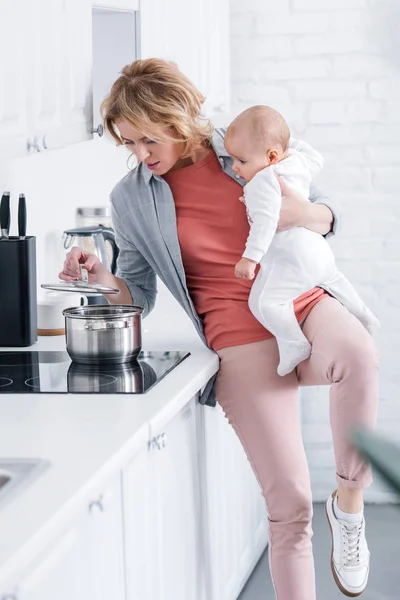 Exausto Mãe Segurando Adorável Criança Infantil Cozinhar Cozinha — Fotografia de Stock