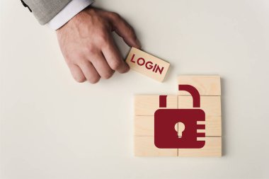 Tuğla 'login' yazı ile üzerine beyaz izole kilit simgesi ile ahşap blokları üzerinde tutan adamın kısmi görünümü