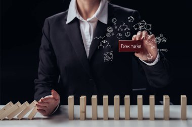 cropped view of businesswoman holding red brick with words 'forex market' while preventing wooden blocks from falling, icons on foreground clipart