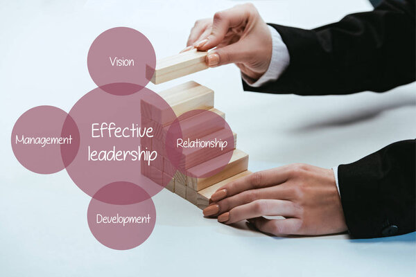 cropped view of man building career ladder with wooden blocks, components of effective leadership on foreground
