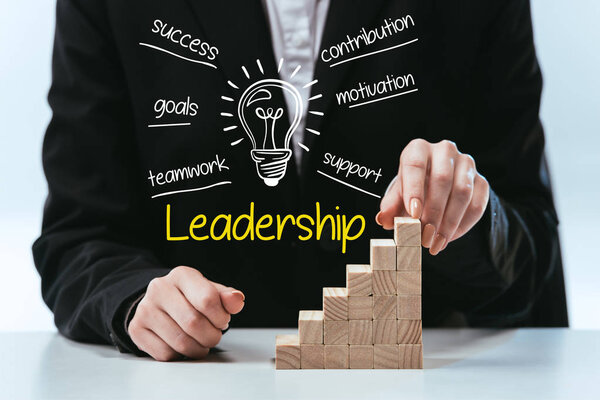 cropped view of woman with wooden career ladder, components of leadership on foreground