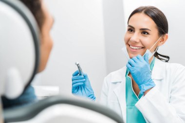 hastanın yakınındaki matkap tutan gülümseyen kadın stomatologist 