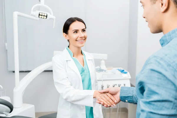 Sorridente Dentista Feminino Apertando Mãos Com Paciente Afro Americano — Fotografia de Stock