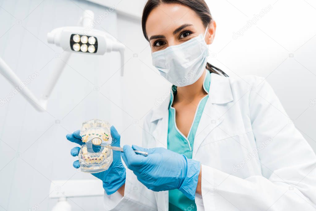 female stomatologist showing dental jaw model with braces 