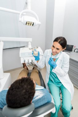 kadın stomatologist hastaya sandalyede diş çene modeli diş telleri ile gösterilen gülümseyen