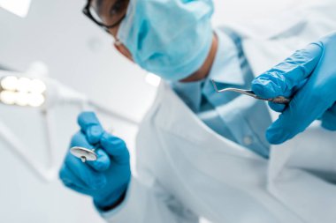 seçici odak elinde bir gözlük ve Maske alanlarındaki erkek dişçi diş aletleri
