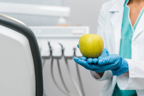 cropped view of apple in hands of female dentist 