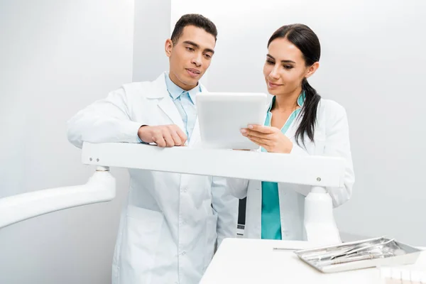 Médicos Multiculturales Pie Batas Blancas Mirando Tableta Digital —  Fotos de Stock