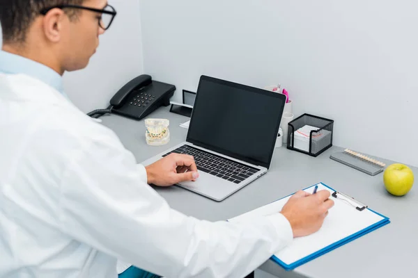 Foco Seletivo Dentista Masculino Fazendo Anotações Usando Laptop Com Tela — Fotografia de Stock