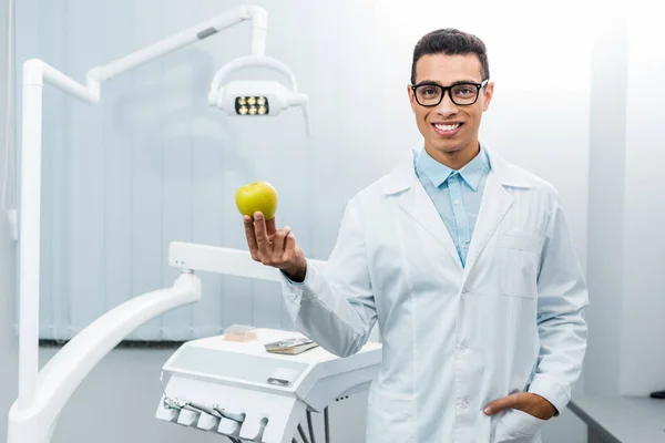 Sonriente Dentista Afroamericano Con Mano Bolsillo Sosteniendo Manzana —  Fotos de Stock