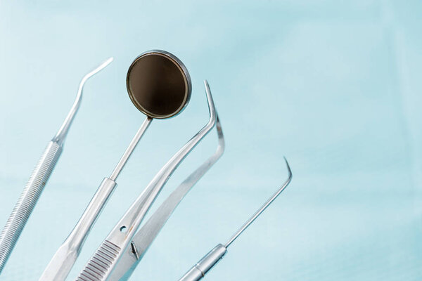 close up of dental mirror near metallic medical instruments