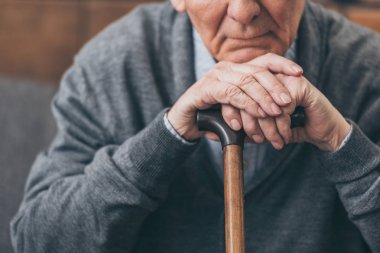 cropped view of upset retired man with walking cane clipart