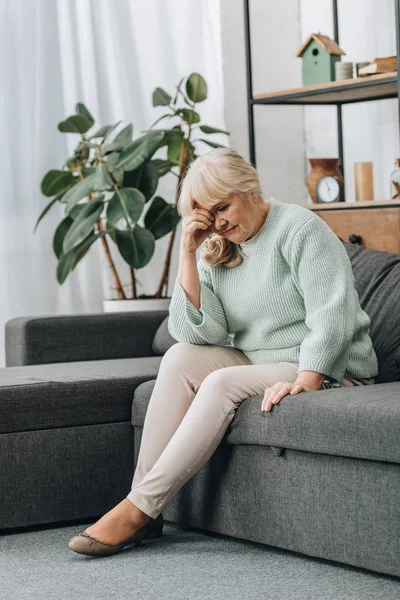 心烦意乱的退休妇女坐在客厅的沙发上 — 图库照片