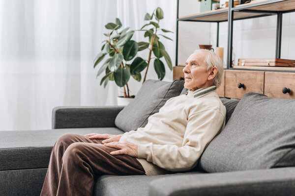 retired man with grey hair sitting on sofa 