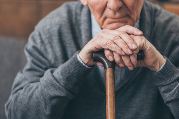 cropped view of upset retired man with walking cane