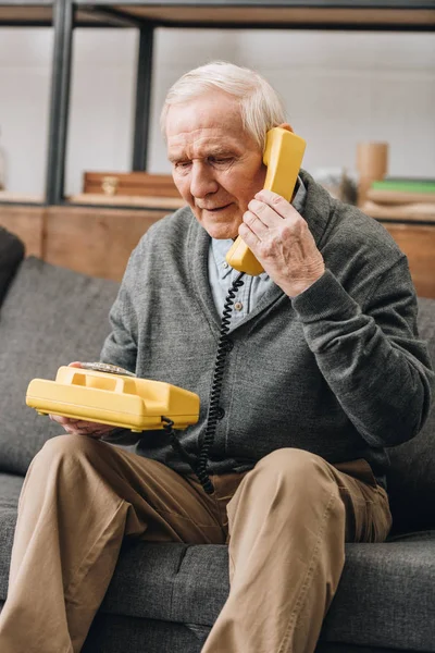 Συνταξιούχος Άνθρωπος Χρησιμοποιώντας Παλιό Τηλέφωνό Σας Ενώ Κάθεστε Στον Καναπέ — Φωτογραφία Αρχείου