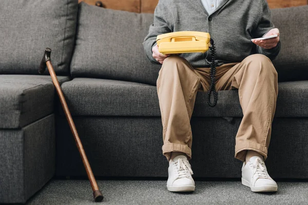 Cropped View Retired Man Holding Smartphone Retro Phone While Sitting — Stock Photo, Image