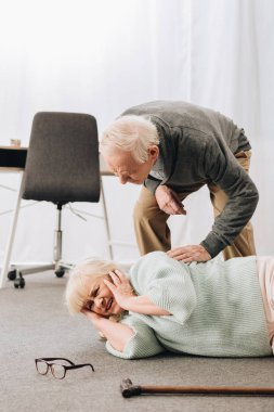 old men helping wife who falled down on floor  clipart