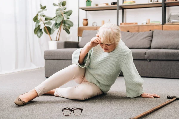 Seniorin Sitzt Wohnzimmer Auf Dem Boden Und Hat Kopfschmerzen — Stockfoto