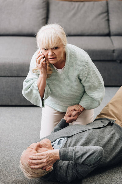 senior woman helping old husband who falled down on floor 