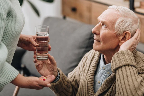 Seniorin Nimmt Glas Wasser Und Tabletten Von Ehemann — Stockfoto