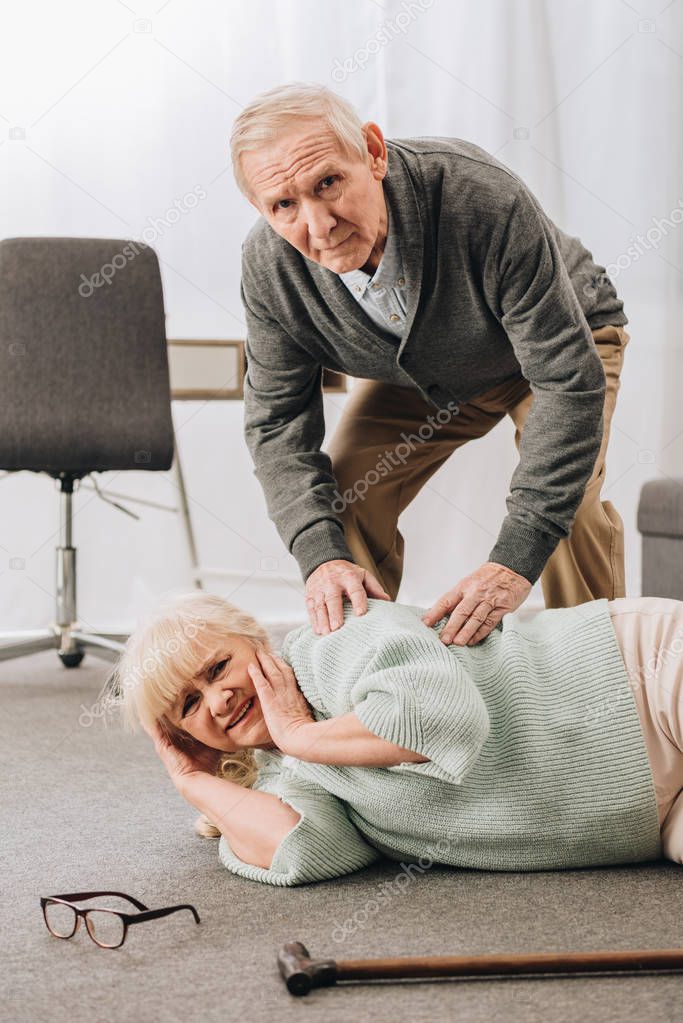 old men helping wife who falled down on floor  and looking at camera