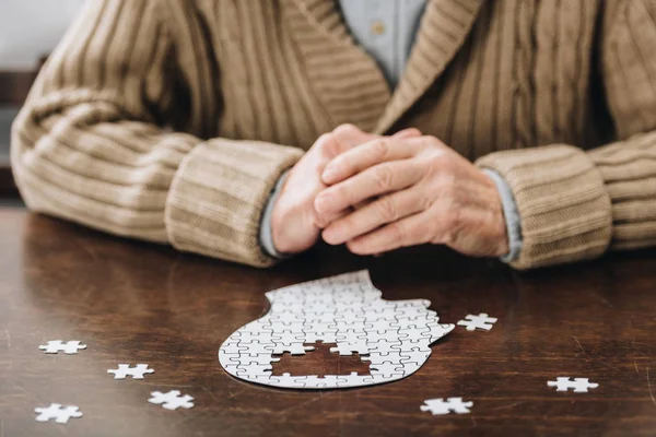 年配の男性がテーブルの上のパズルで遊んでのトリミング ビュー — ストック写真