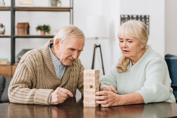 senior couple playing with wooden blocks at home