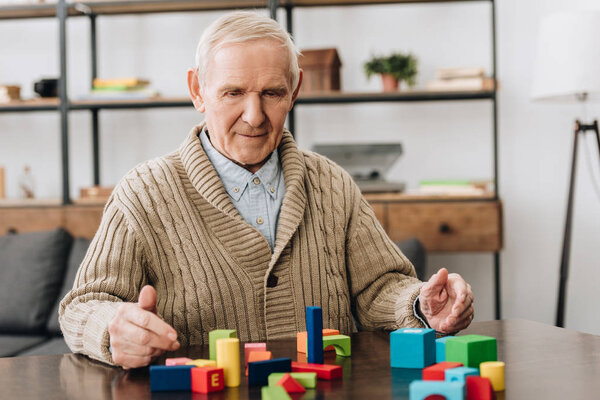senior man playing with wooden toys on table