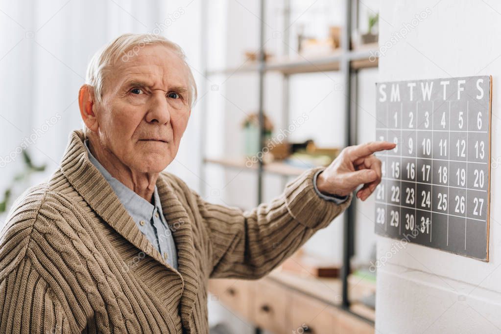 old man touching calendar looking at camera