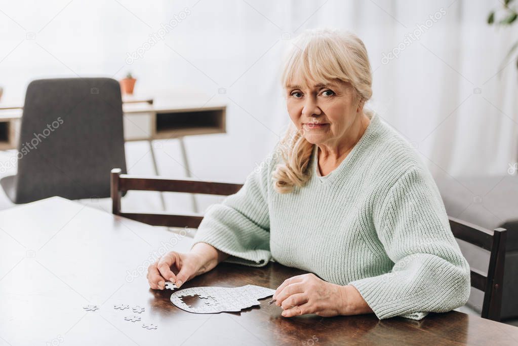 blonde retired woman playing with puzzles at home 
