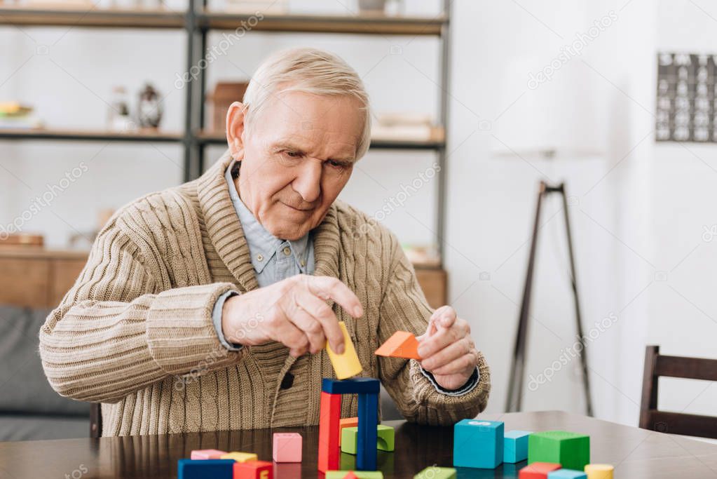 retired man playing with wooden toys at home