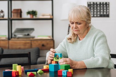 senior woman playing with wooden toys at home clipart