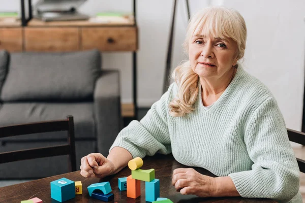 Mulher Aposentada Com Cabelo Loiro Sentado Perto Brinquedos Madeira Casa — Fotografia de Stock